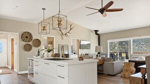 A spacious kitchen with a central island, a ceiling fan, and a dining area with a view. - LUX Guest FAV + Stunning Views + Yoga Deck + Spa (Big Bear)