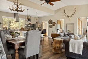 A spacious living area with a dining table, grey upholstered chairs, a wooden coffee table, and a ceiling fan. - LUX Guest FAV + Stunning Views + Yoga Deck + Spa (Big Bear)