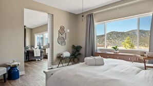 A hotel room with a large bed, a desk, a window with a mountain view, and a ceiling fan. - LUX Guest FAV + Stunning Views + Yoga Deck + Spa (Big Bear)