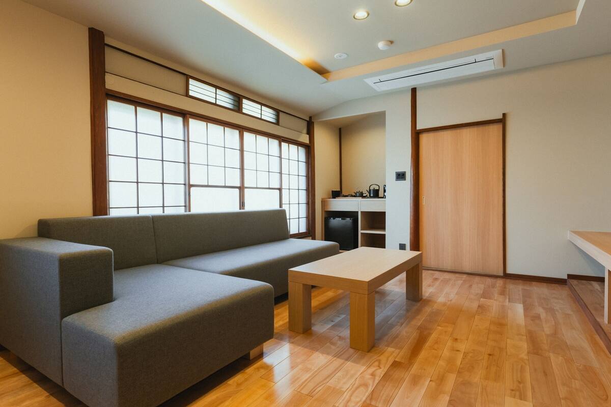 Una sala de estar moderna con un sofá, una mesa de centro, una zona de cocina y una puerta corredera.