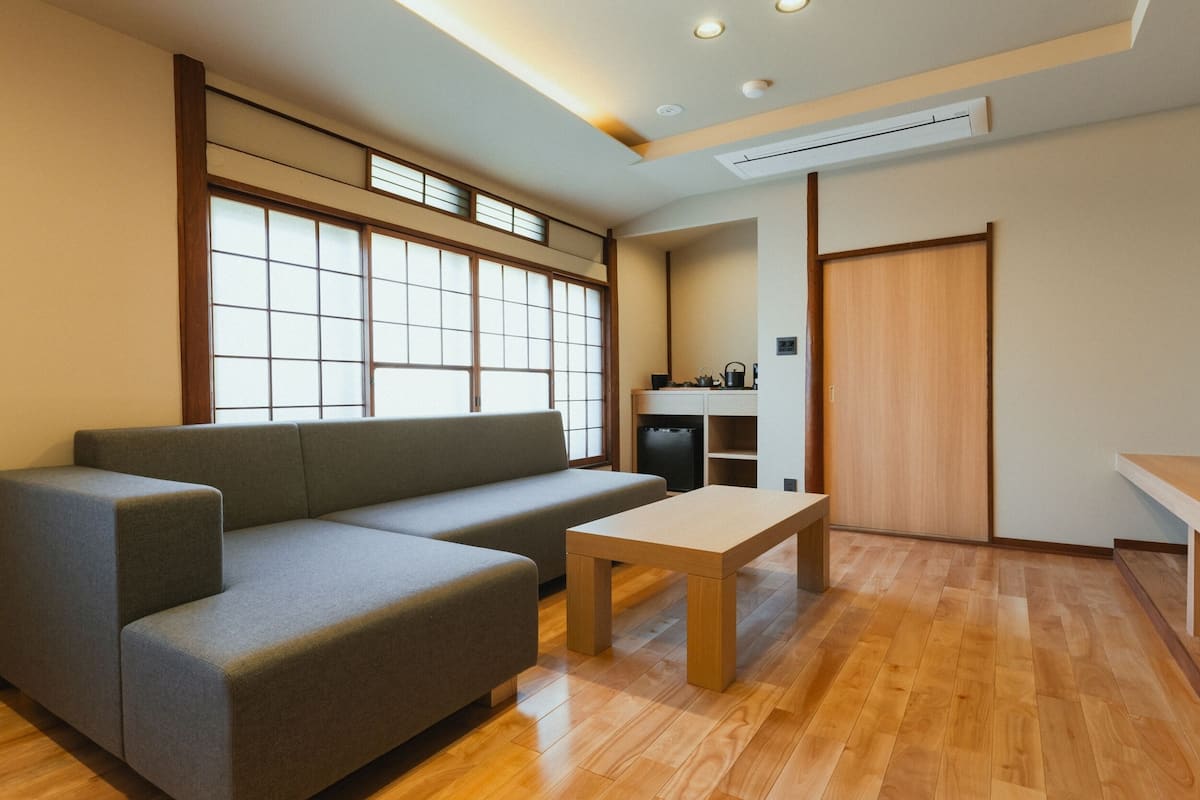 A modern living room with a sofa, a coffee table, a kitchen area, and a sliding door.