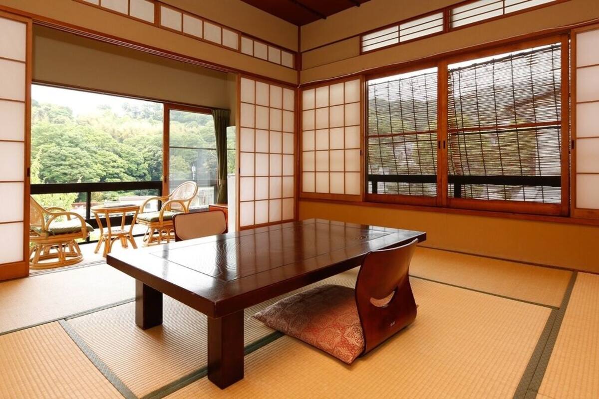 Una habitación japonesa tradicional con suelo de tatami, una mesa baja y puertas correderas shoji.