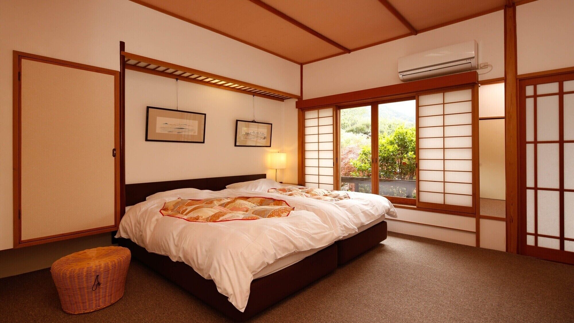 A traditional Japanese-style bedroom with tatami flooring, a futon bed, sliding shoji doors, and an air conditioning unit.