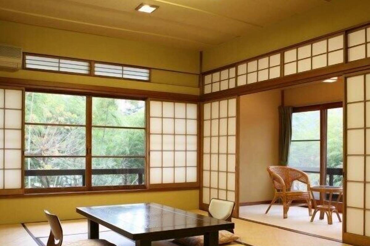 Una habitación japonesa tradicional con suelo de tatami, una mesa baja y puertas correderas.
