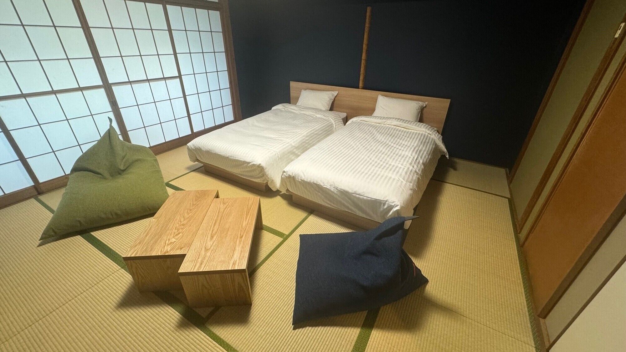 A traditional Japanese-style room with tatami flooring, two beds, and a low wooden table.