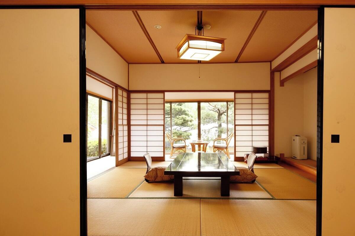 Una habitación japonesa tradicional con suelo de tatami, una mesa baja y puertas correderas.