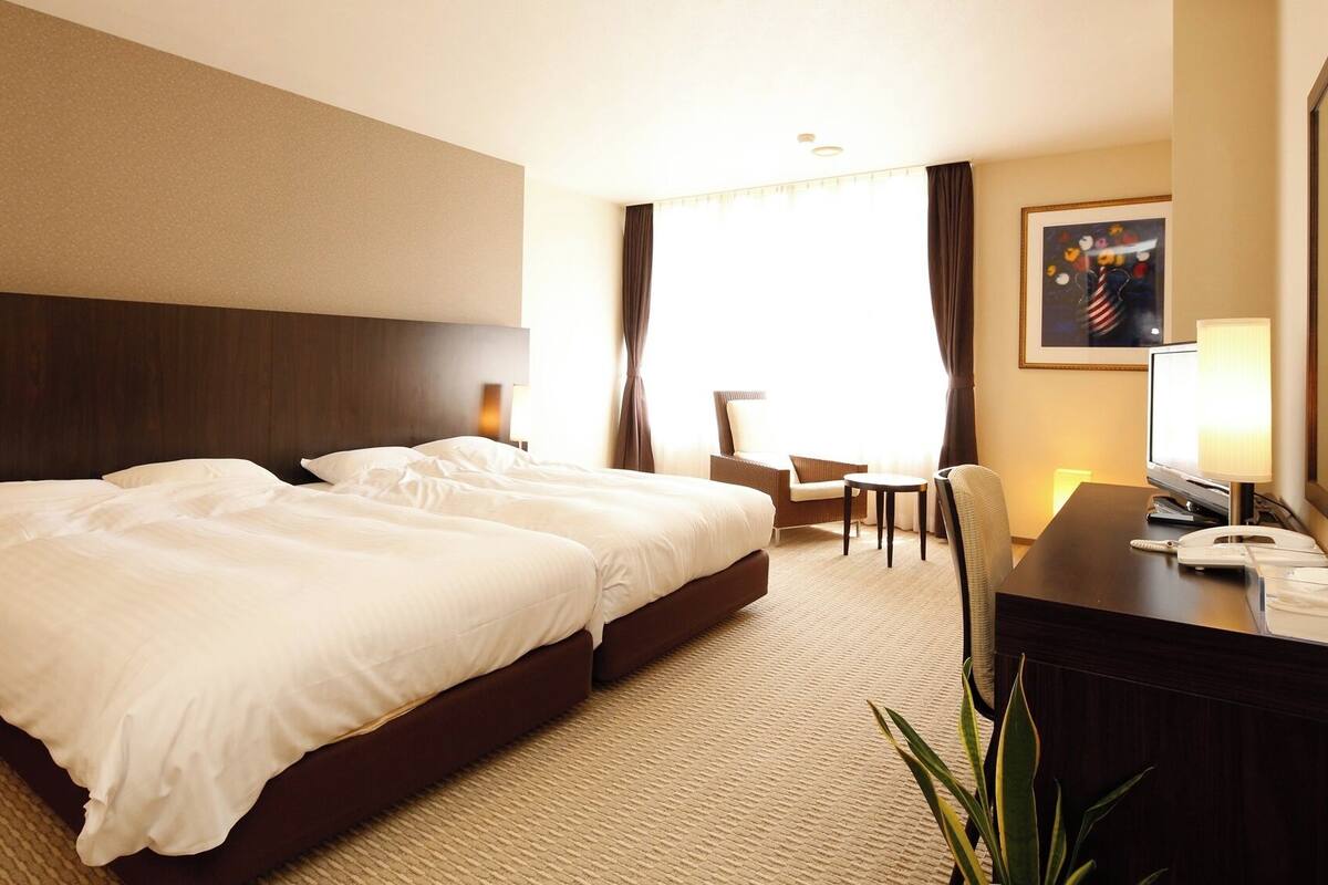 Una habitación de hotel con una cama grande, un escritorio con teléfono, una silla y una televisión.