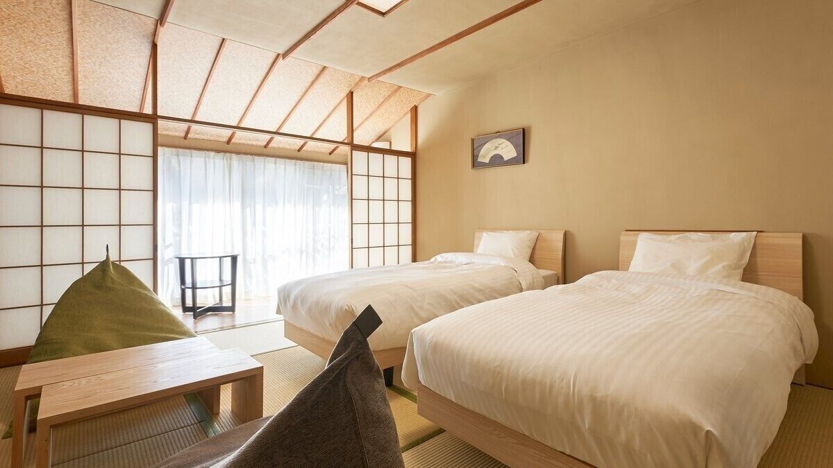 A hotel room with two beds, a tatami mat table, and a sliding shoji screen.