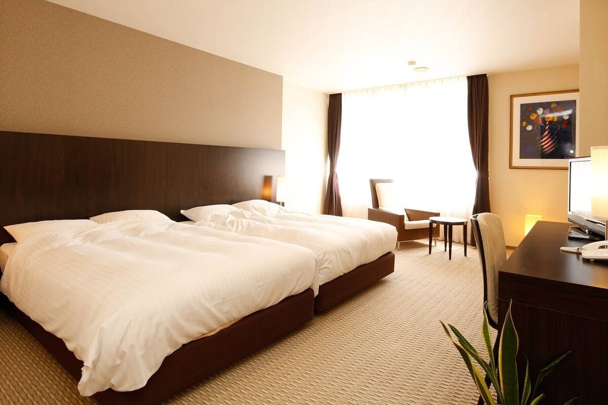 Una habitación de hotel con una cama grande, un escritorio, un teléfono, una silla y una mesita.