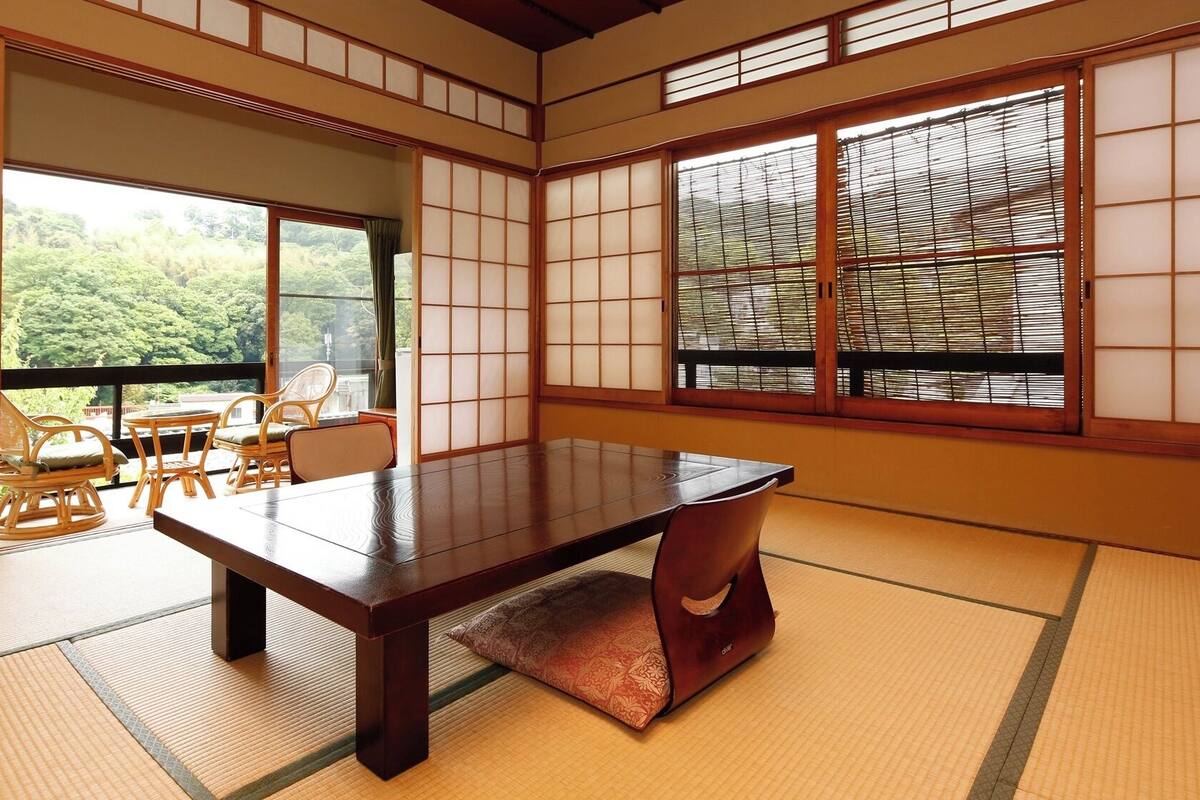 Una habitación japonesa tradicional con suelo de tatami, una mesa baja y puertas correderas.