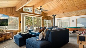 Ein gemütliches Wohnzimmer mit einer großen Couch, einer Holzbalkendecke und einem Billardtisch.