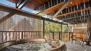 Ein Außenbereich mit Whirlpool, einer Holzterrasse, einem Metallgeländer und einer Pergola.