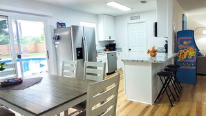 A modern kitchen with white cabinets, stainless steel appliances, and a wooden dining table with chairs.