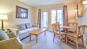 A living room with a sofa, a wooden coffee table, and a dining table with chairs. - Classic Spacious Studio Suite! (Shanty Bay)