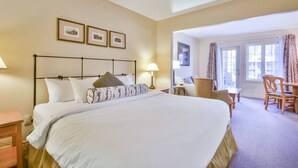 A hotel room with a large bed, a desk, a chair, and a window with curtains. - Classic Spacious Studio Suite! (Shanty Bay)