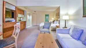A compact hotel room with a kitchenette, a sofa, a chair, a small table, and a bed. - Classic Spacious Studio Suite! (Shanty Bay)