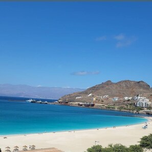 A coastal beach scene with clear blue waters, a sandy beach, and a mountainous backdrop. - Cozy 2-Bedroom Condo with WiFi, AC in Mindelo, Sao Vicente, Cape Verde (Mindelo)