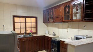Una cocina con armarios de madera, horno empotrado, pileta y ventana con vidrio esmerilado.