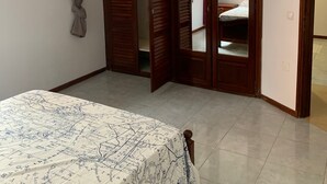 Un dormitorio con cama, armario y espejo.