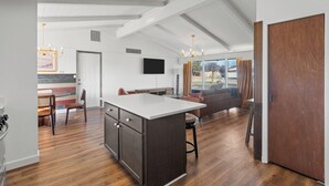 Een ruime keuken met een groot eiland, houten vloeren en een zithoek met een bank en stoelen.