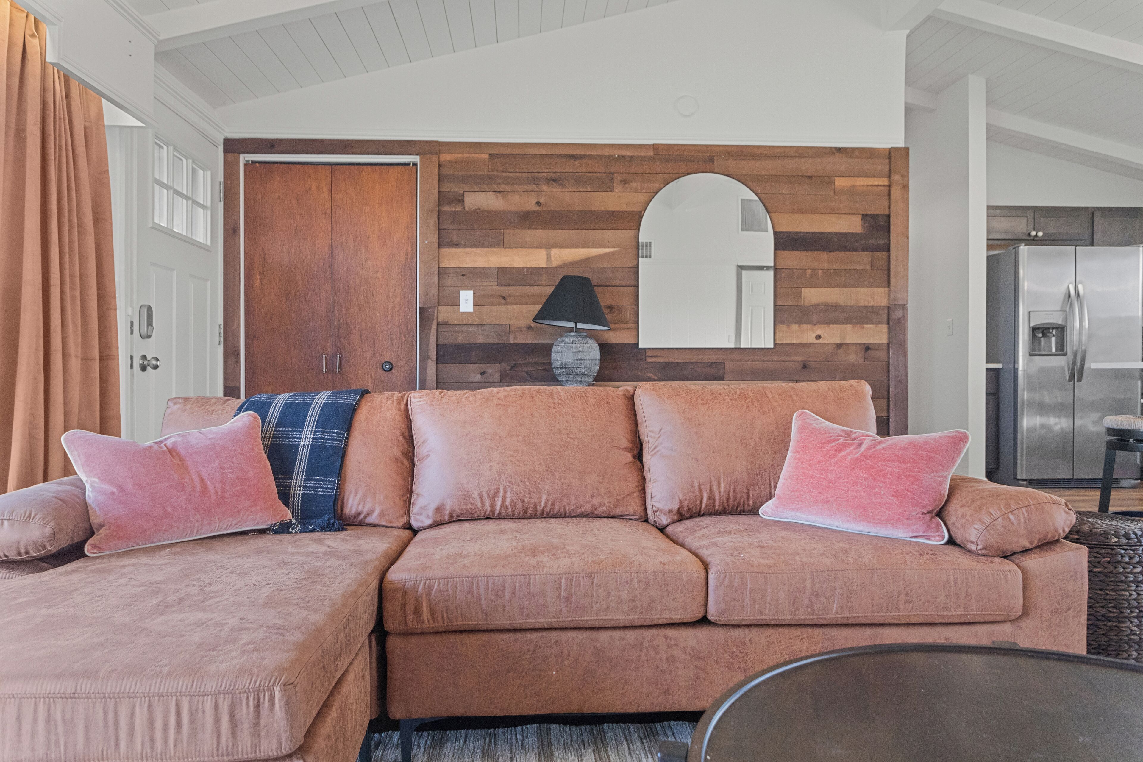 Una sala de estar con un sofá modular, una lámpara y un panel de pared de madera.