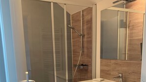 A modern bathroom with a glass shower enclosure, a white vanity with a sink, and a mirror above the vanity.