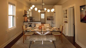 Un coin repas avec une table en verre, des chaises en bois et un banc à motifs.