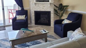 A living room with a fireplace, a flat-screen TV, and two armchairs. - Oceans Edge 503 on the Boardwalk at 9th St (Ocean City)