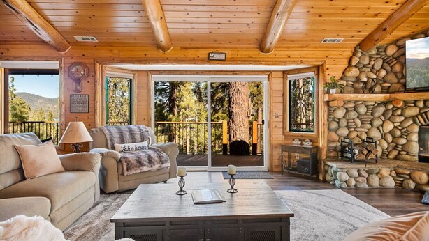 A cozy log cabin interior with a sofa, coffee table, and fireplace.