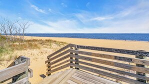Una pasarela de madera bordeando una playa de arena, con vista despejada al océano.