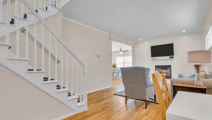 Una sala de estar moderna con una escalera, una chimenea y un televisor.