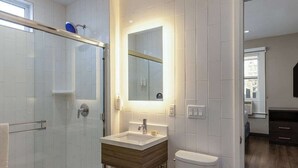 Un bagno moderno con cabina doccia in vetro, un mobile bagno in legno, un water bianco e uno specchio grande.