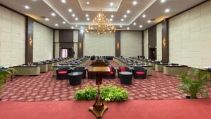A large conference room with rows of tables and chairs, a central podium, and a chandelier. - Merapi Merbabu Hotels Bekasi (Rawalumbu)