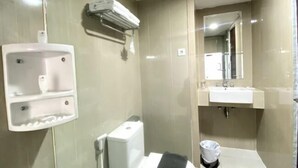 A modern bathroom with a built-in sink, a mirror, and a towel rack. - Merapi Merbabu Hotels Bekasi (Rawalumbu)
