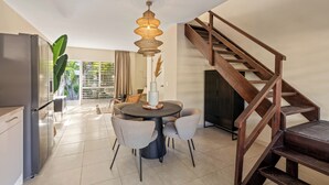 A modern kitchen with a dining area, a staircase, and a view of the outdoors.
