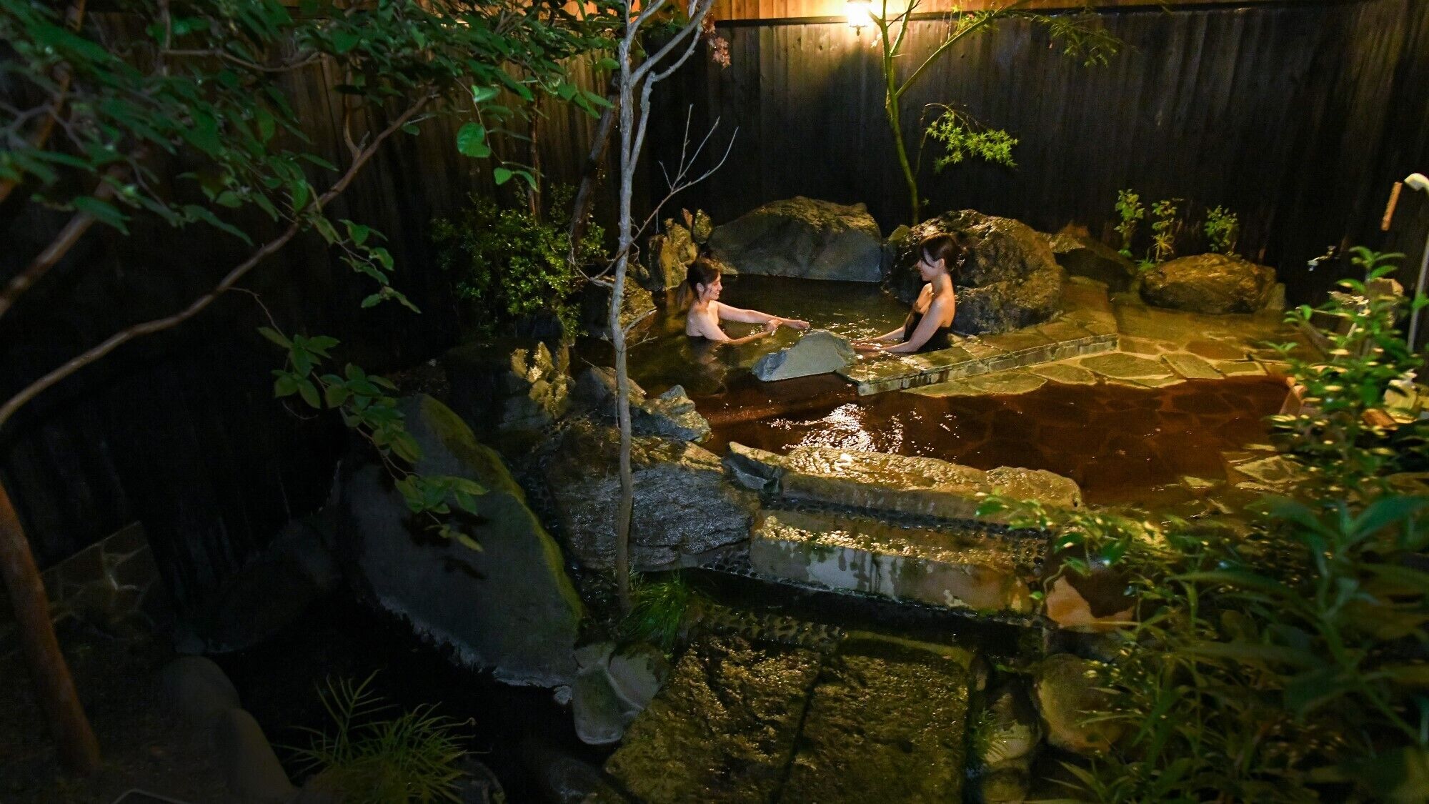 Un área de aguas termales con formaciones rocosas naturales y vegetación.