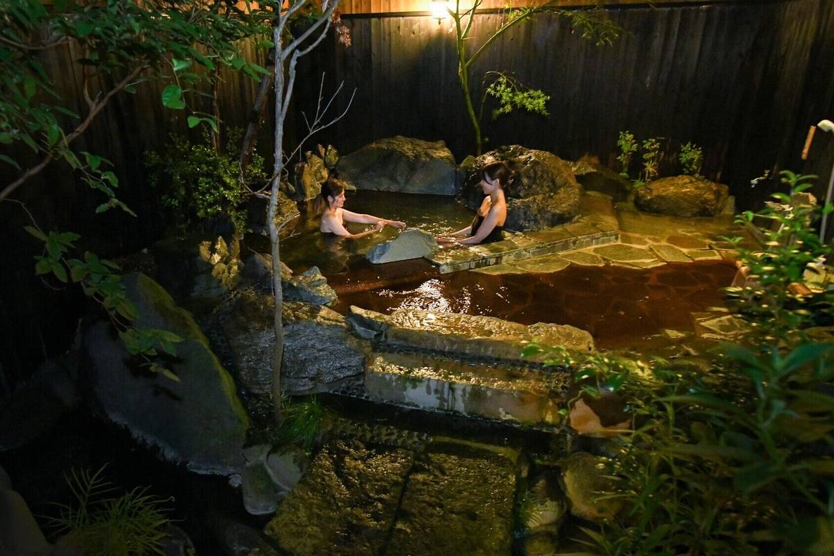 A hot spring area with natural rock formations and greenery.