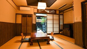 Ein traditioneller japanischer Raum mit Tatami-Bodenbelag, einem niedrigen Tisch und Schiebetüren.