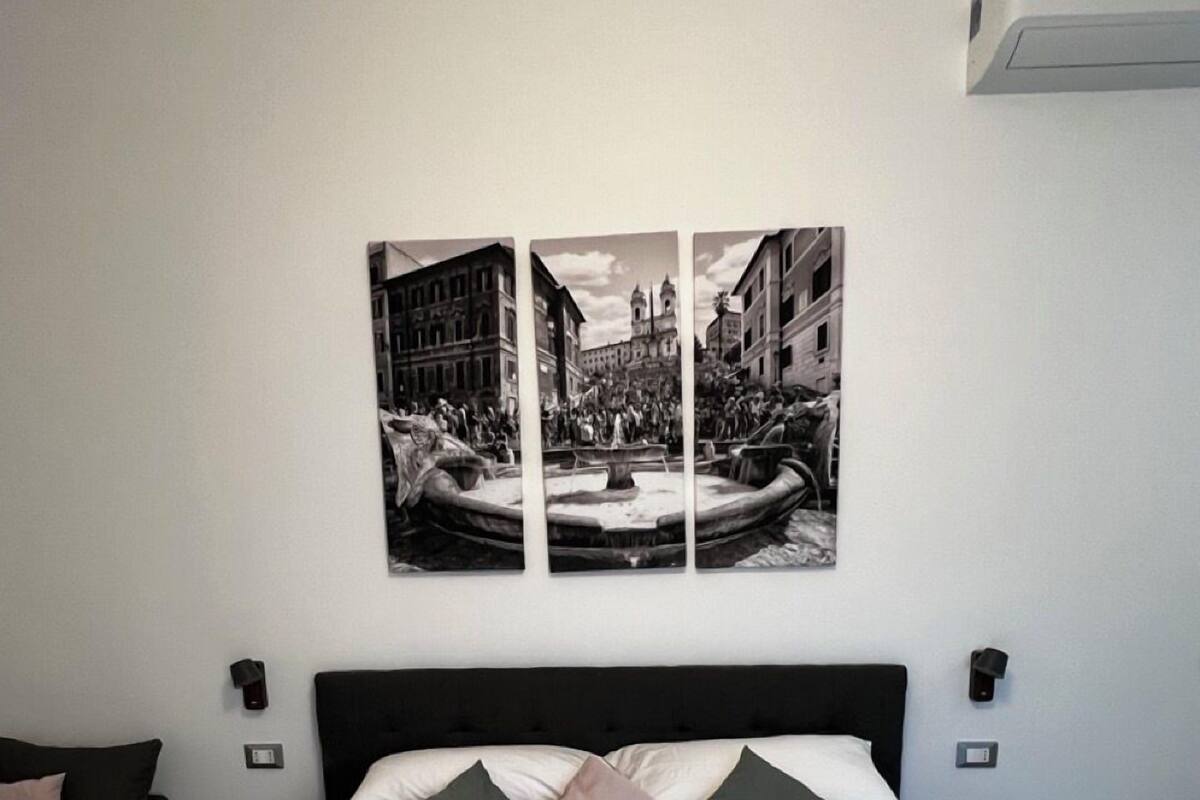Una cama bien hecha con ropa de cama blanca y dos almohadas, un cabecero negro y un aire acondicionado de pared.