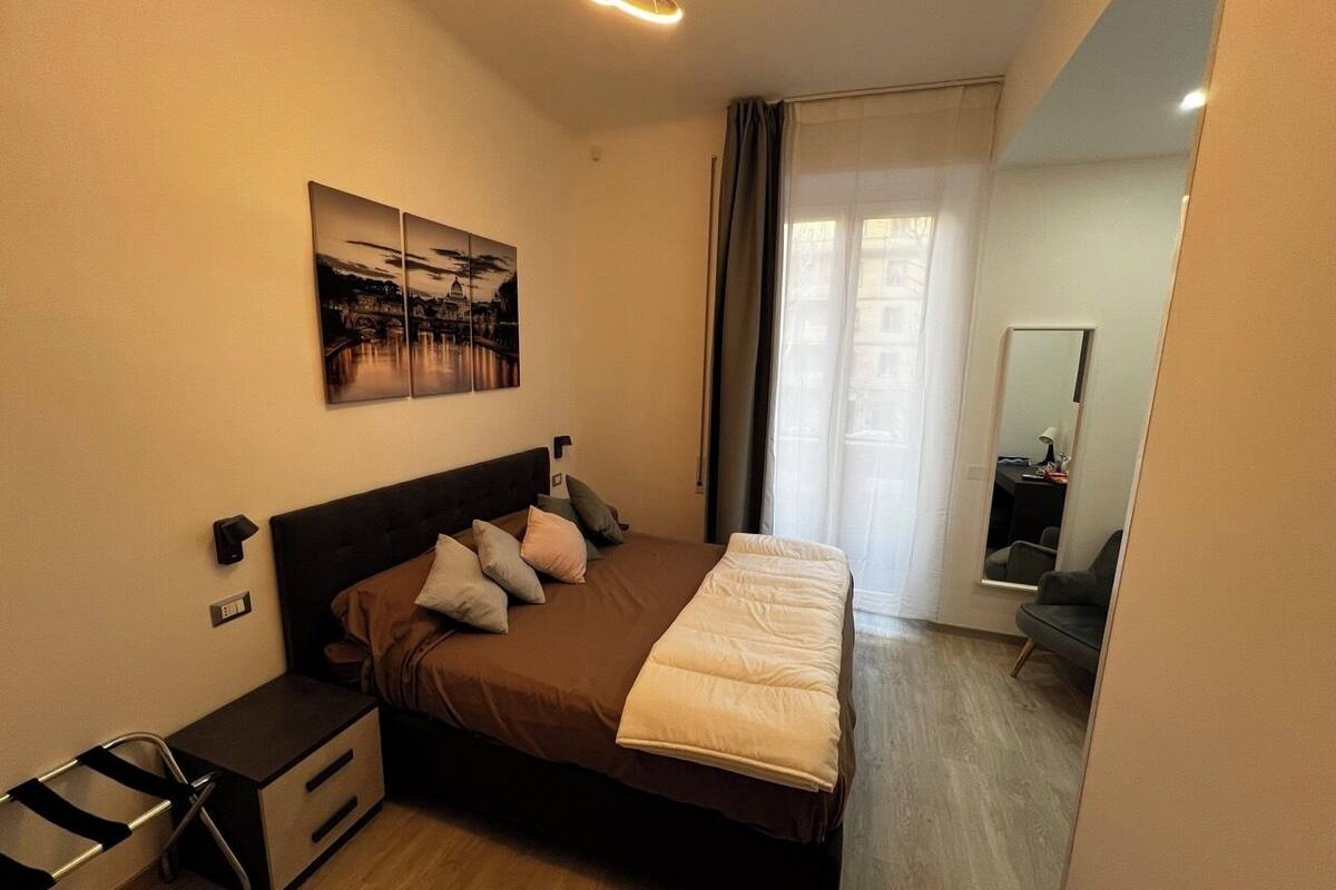 Un dormitorio con cama, mesitas de noche, un espejo y un cuadro en la pared.