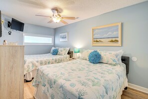 A bedroom with two beds, a ceiling fan, a TV, and a beach-themed painting. - Walk to Beach: Top-Floor Condo in Murrells Inlet (Murrells Inlet)