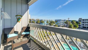 A balcony with wicker furniture, a welcome sign, and a sign indicating the direction to the beach.