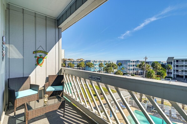 A balcony with wicker furniture, a welcome sign, and a sign indicating the direction to the beach. - Walk to Beach: Top-Floor Condo in Murrells Inlet (Murrells Inlet)