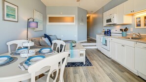 A modern kitchen with white cabinets, a microwave, and a dining area with a table set for four.