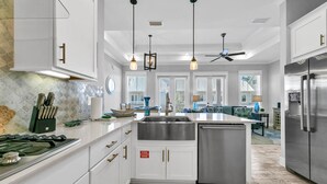 A modern kitchen with white cabinetry, stainless steel appliances, and pendant lighting.