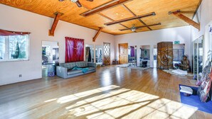 A spacious room with wooden flooring, a ceiling fan, and a large window allowing natural light. - Mtn-View Weldon Home: Walk to Pacific Crest Trail (Weldon)