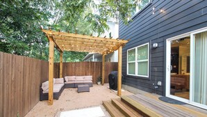 A backyard with a wooden pergola, a sectional sofa, and a barbecue grill. - Modern Cowboy Retreat Near Downtown Lockhart (Lockhart)