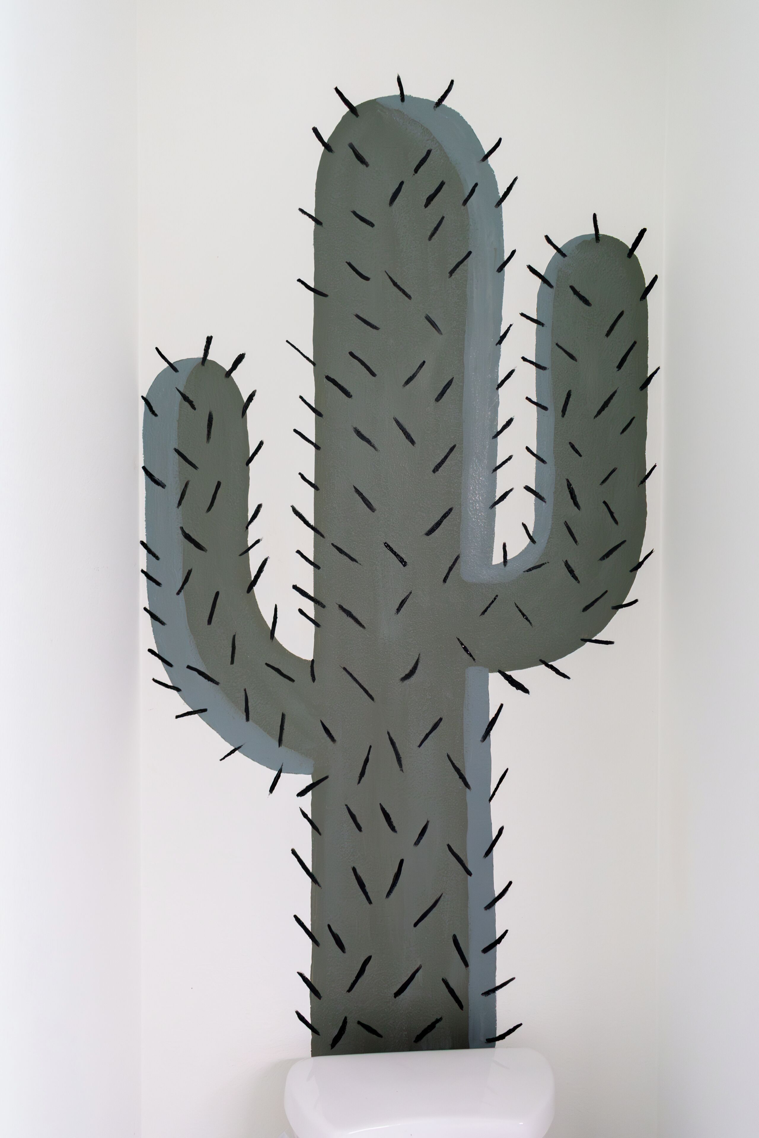 A cactus sculpture with a white base.