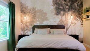 A bedroom with a large bed, a window with green curtains, and a wall mural of trees. - Modern Cowboy Retreat Near Downtown Lockhart (Lockhart)