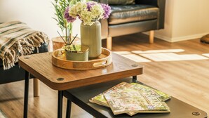 Ein Holztisch mit einem Magazin, einer Vase mit Blumen und einer Schale mit Kerze und Pflanze.